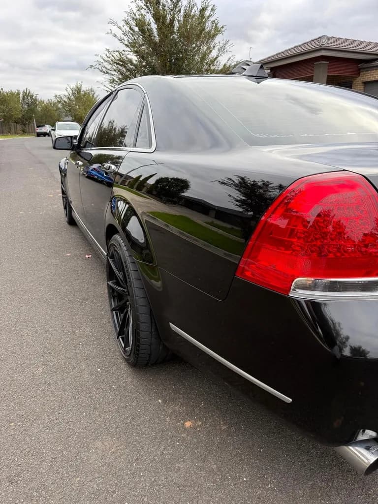 Mirror-finish gloss down the rear quarter of a black Holden Caprice
